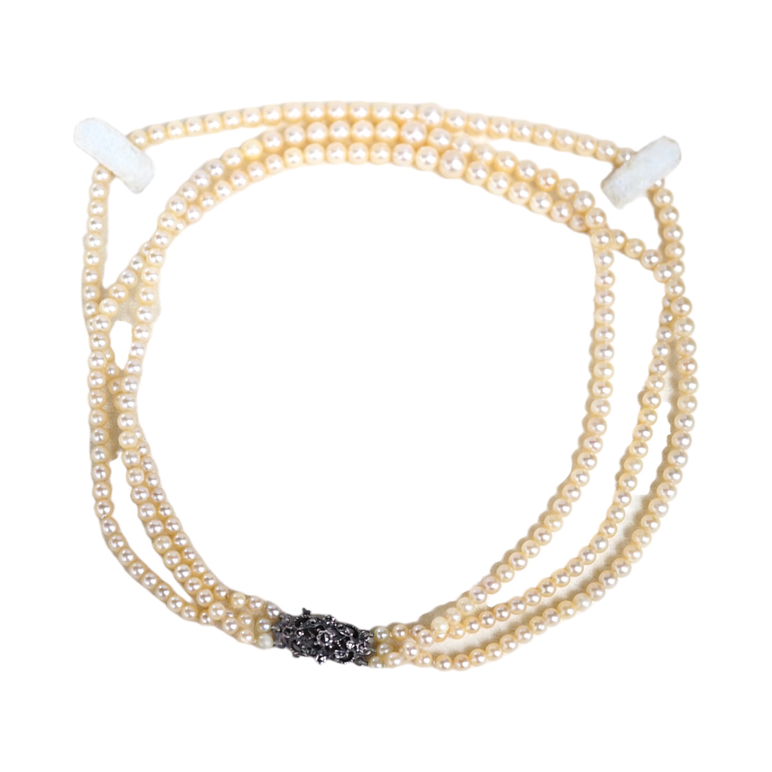 A triple strand graduated cultured pearl necklace, with marcasite set white metal clasp, 40cm. Condition - fair to good.